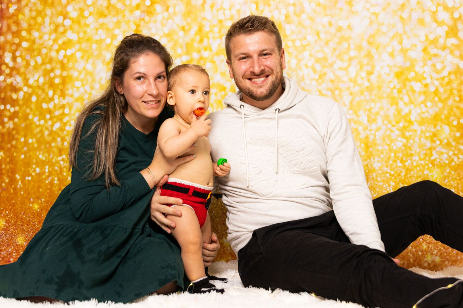 Family holiday portrait against golden sparkly background.