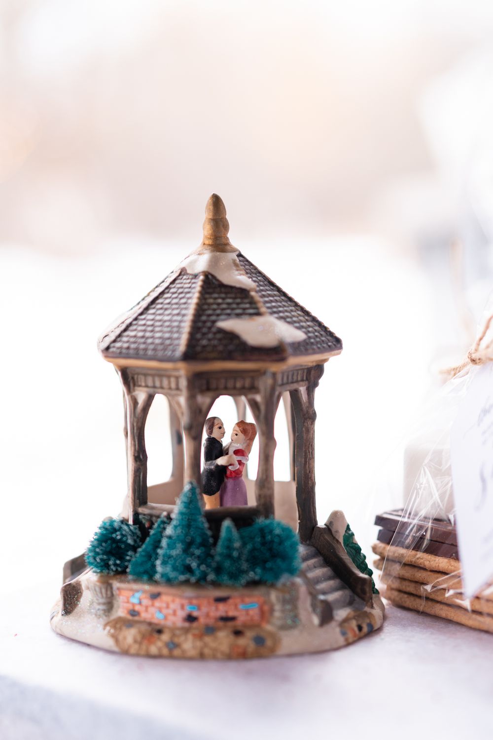 Decorative miniature gazebo wedding cake topper with tiny trees and figures.