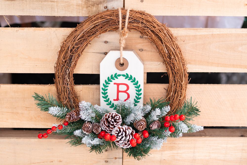 Christmas wreath decorated with pinecones, berries and a monogrammed B tag.