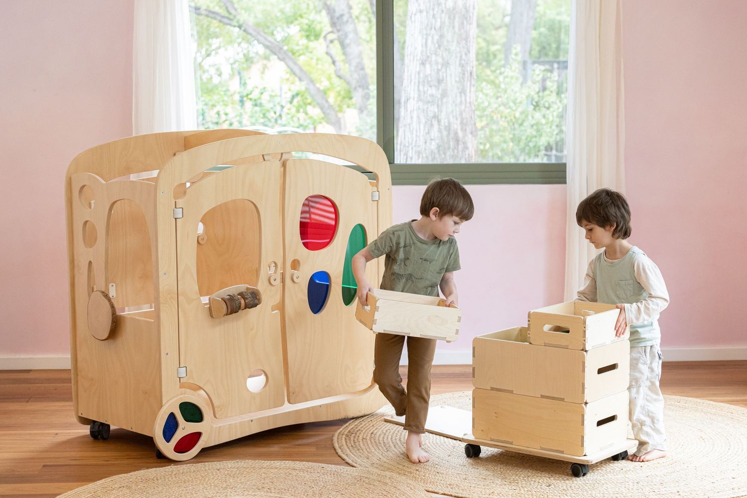 Two children playing with wooden storage boxes in a bright room.