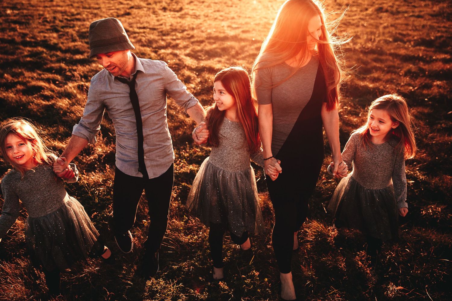 A white family walks hand-in-hand talking and laughing during golden hour. The yellow haze adds beautiful light.
