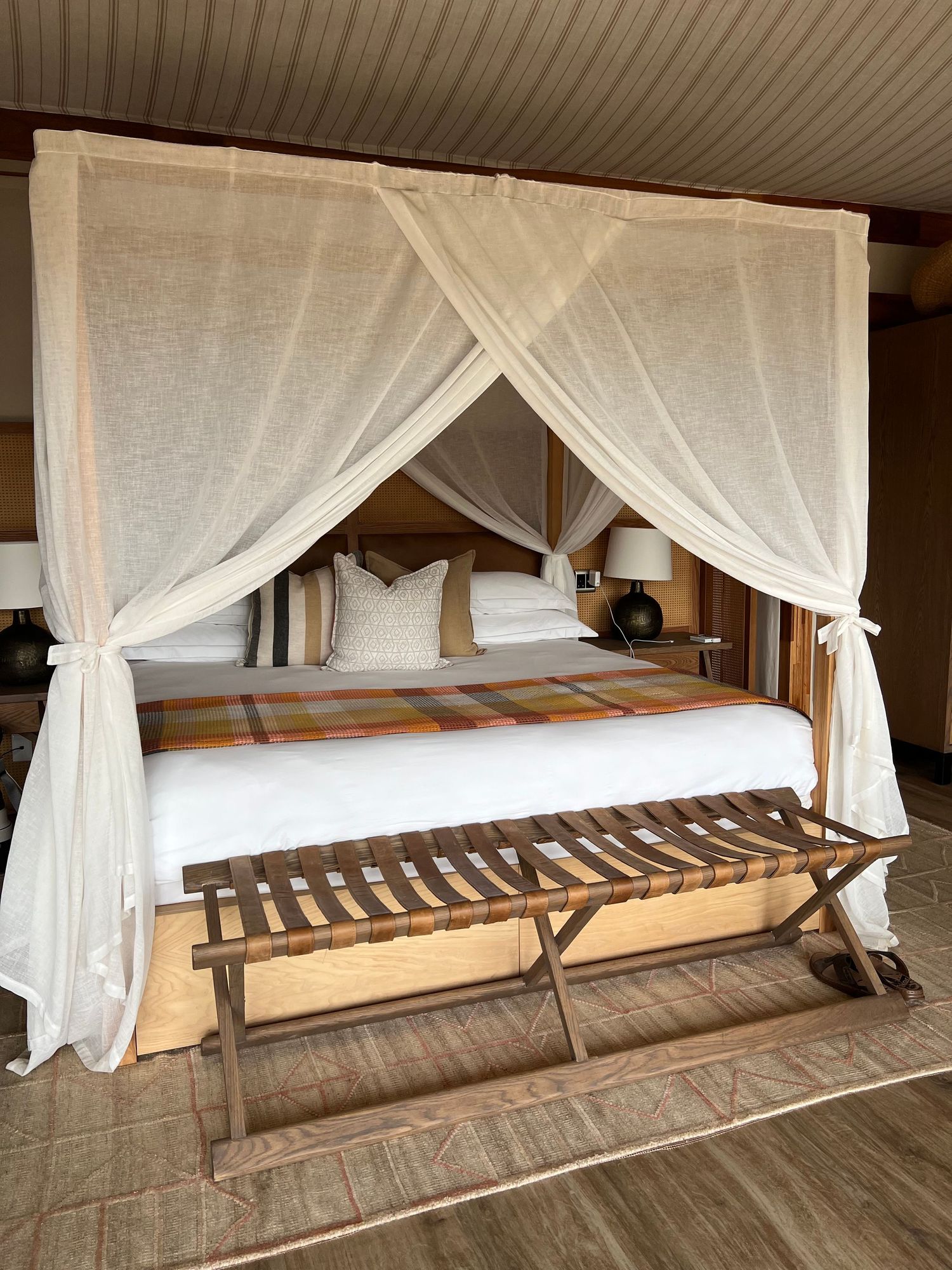 White mosquito nets draped over wooden beds in safari accommodation.