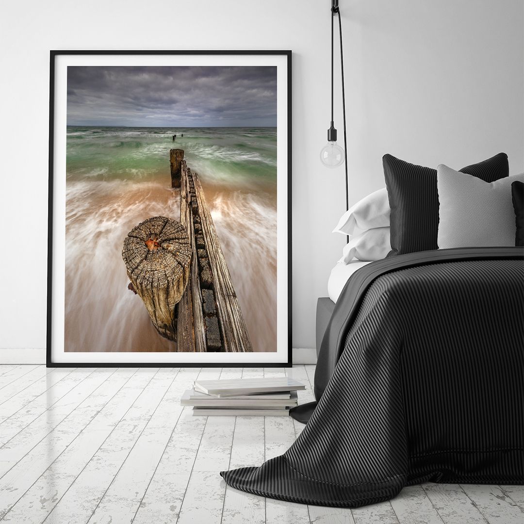 Dramatic seascape photograph showing waves crashing against wooden pier in bedroom setting.