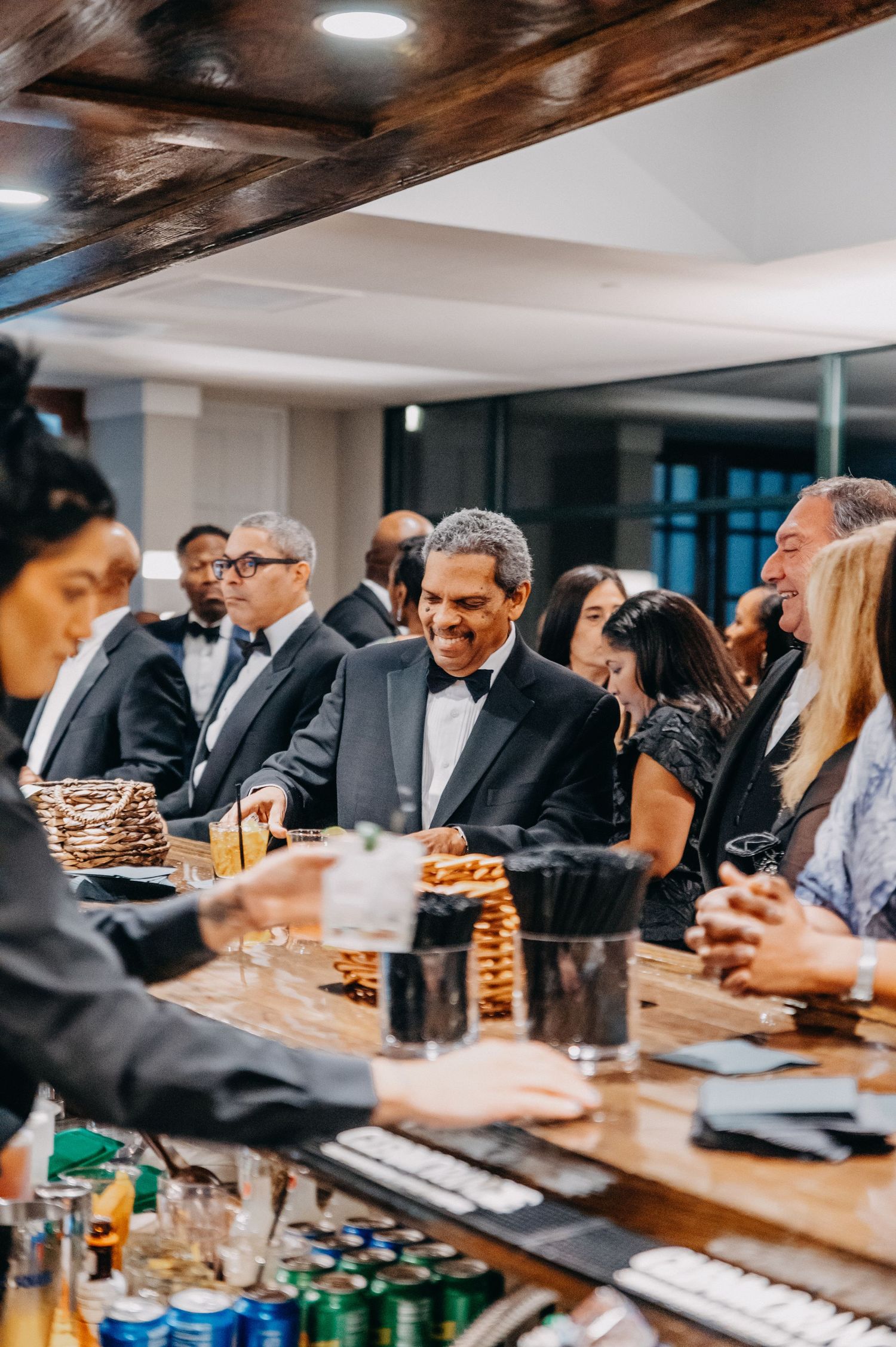Guests in formal attire gather at an elegant bar during upscale evening event.