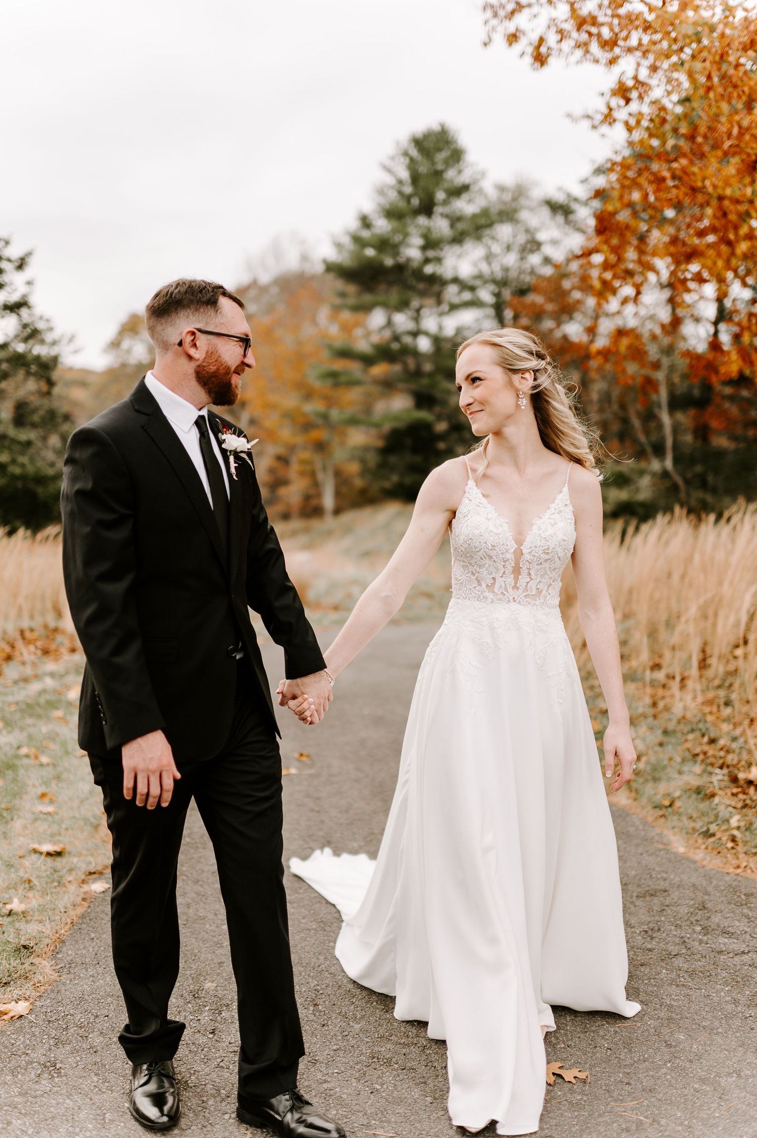 Couple sharing candid moment on path with fall colors and evergreen trees.