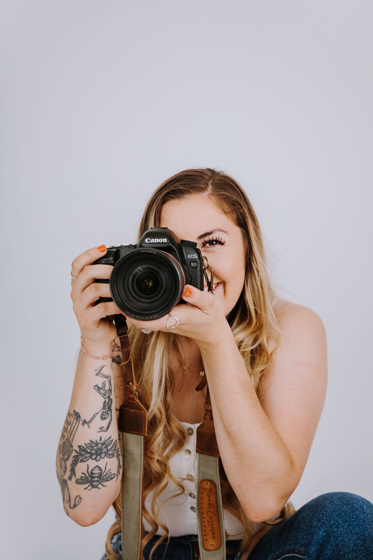 Photographer holding professional camera in artistic self-portrait series against white background.