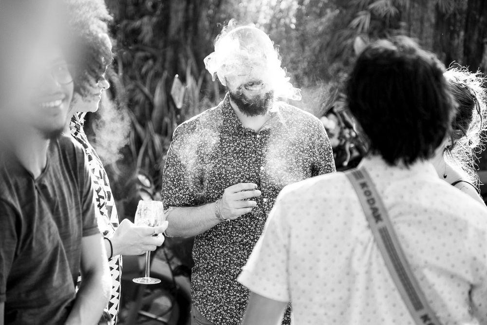 Black and white photo of guests socializing outdoors with sunlight creating a glowing effect.