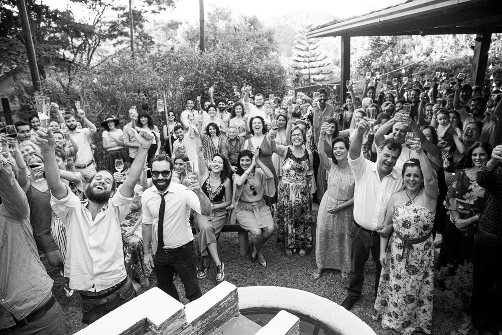 Black and white aerial view of wedding guests gathered together with raised arms celebrating.