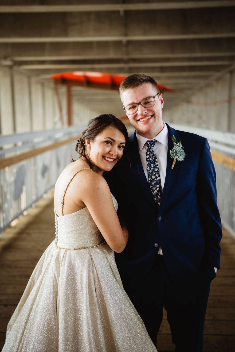 Wedding couple posing in industrial corridor with orange kayak in background.