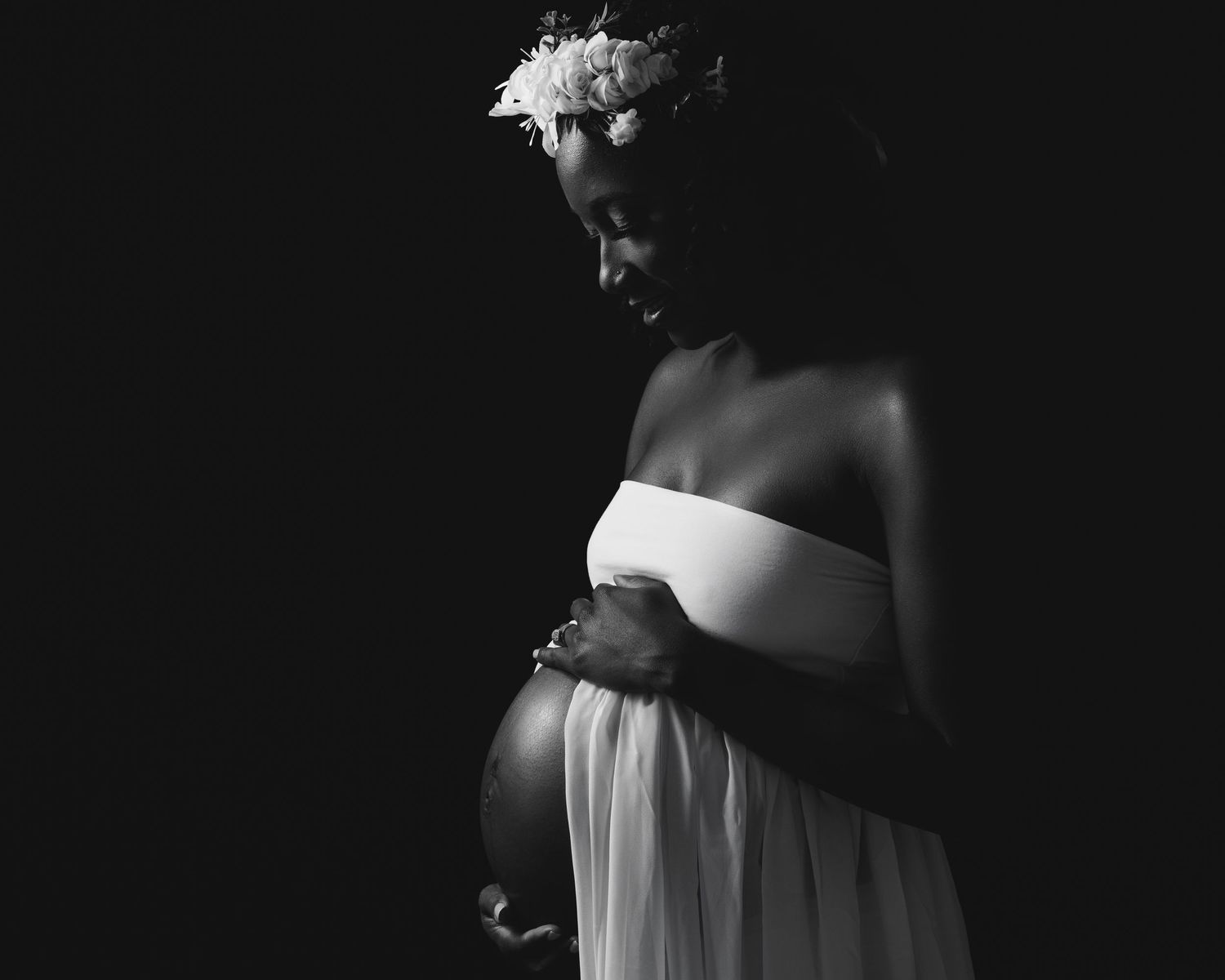 Pregnant Black woman holding belly in black and white