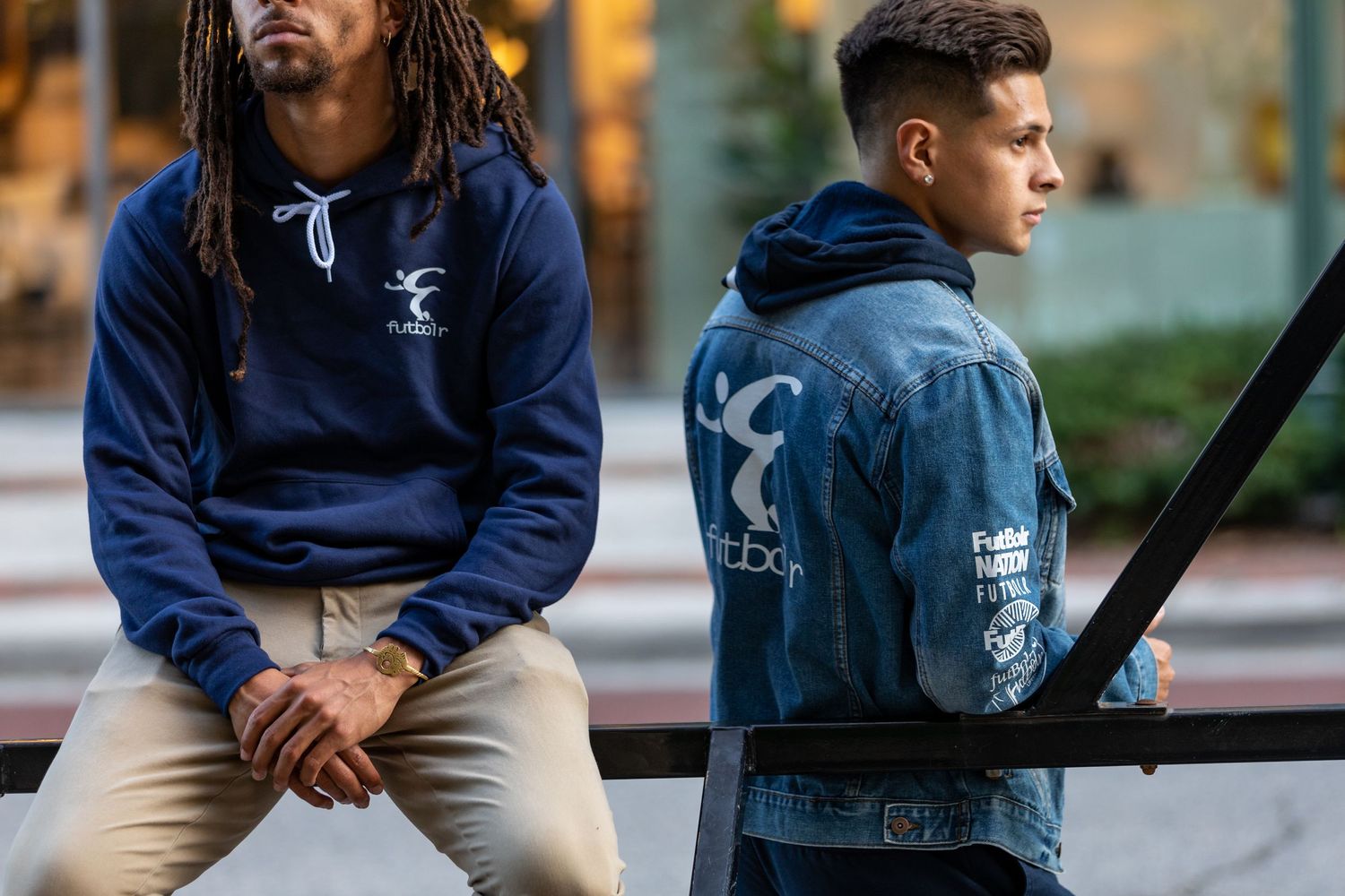Group of young men in casual attire sitting on urban steps during daytime.