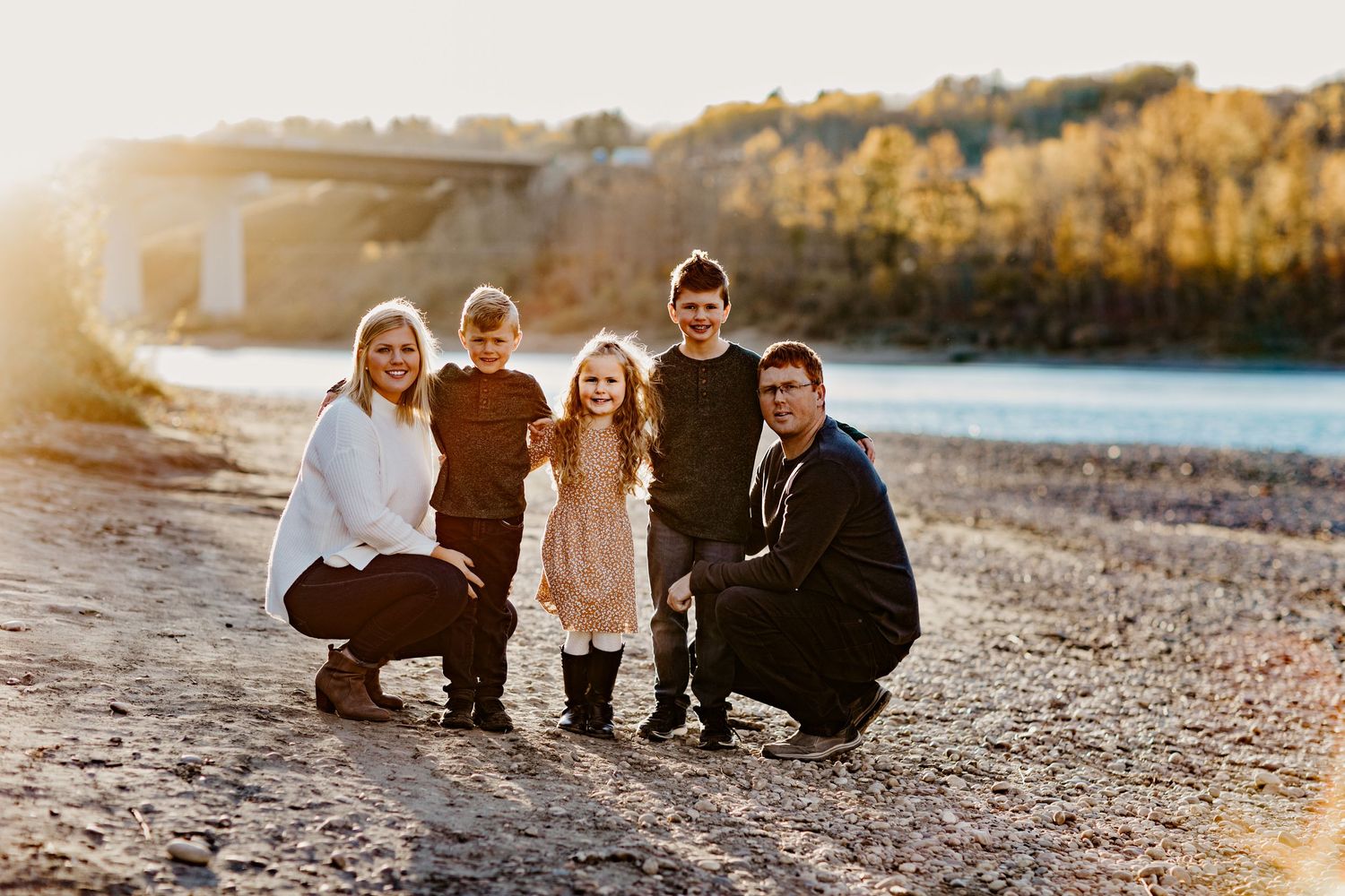 Family poses together at beach during golden hour sunset photoshoot.