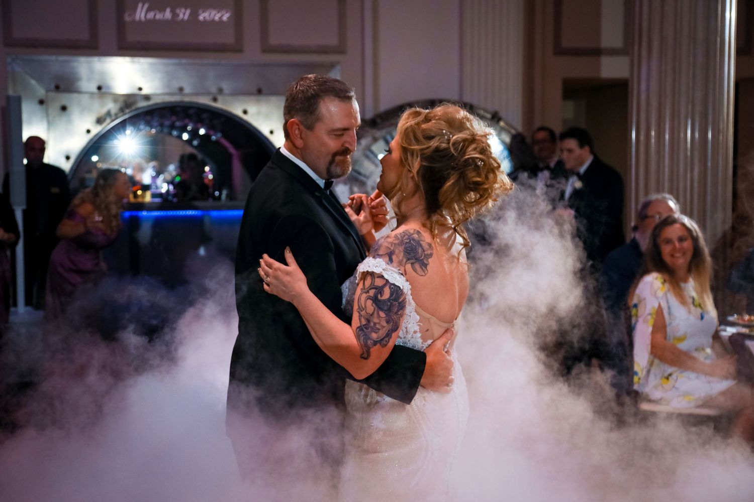 Newlyweds share their first dance surrounded by atmospheric fog effects on the dance floor.