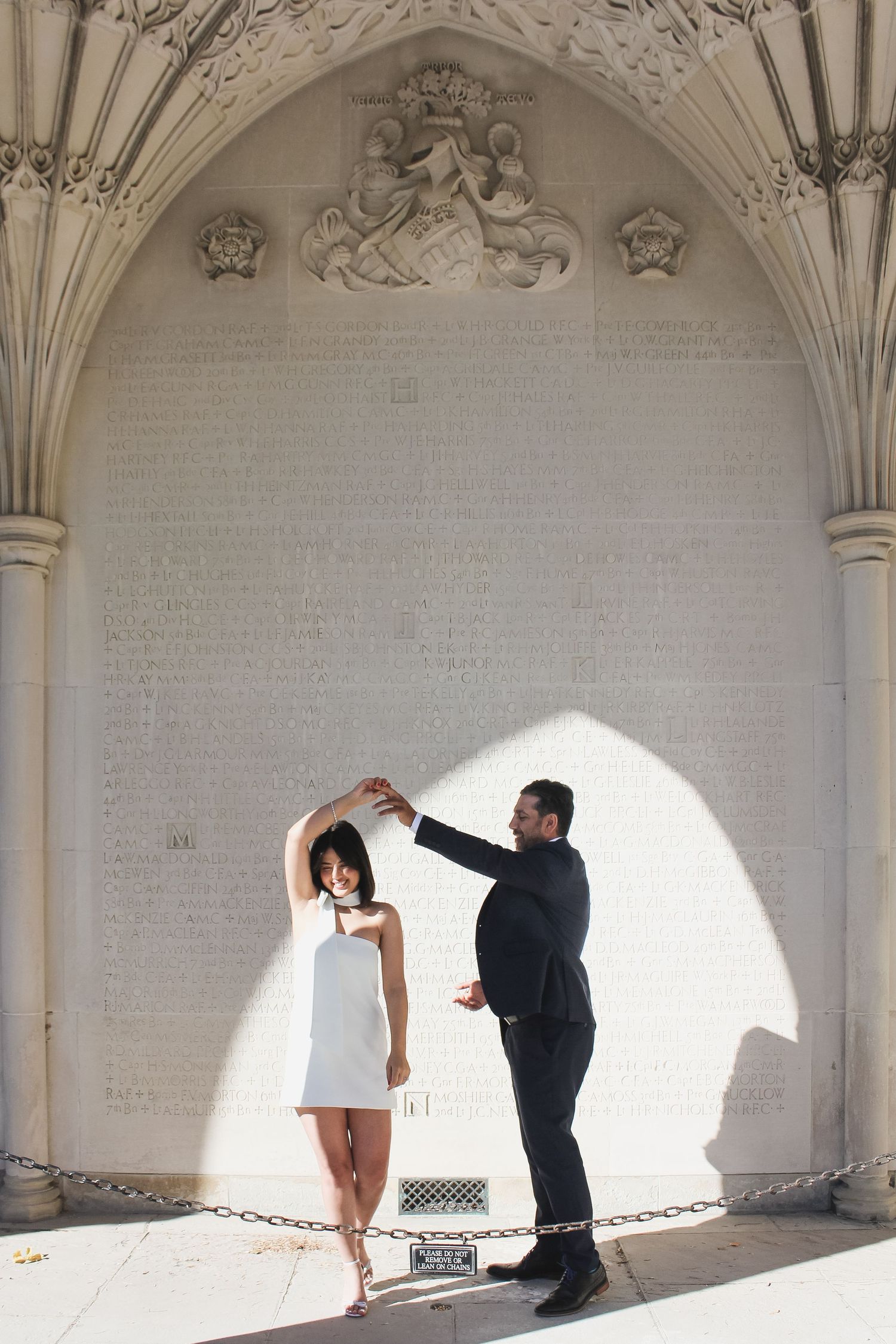A couple dancing in a sunlit archway creating dramatic shadows and light patterns.