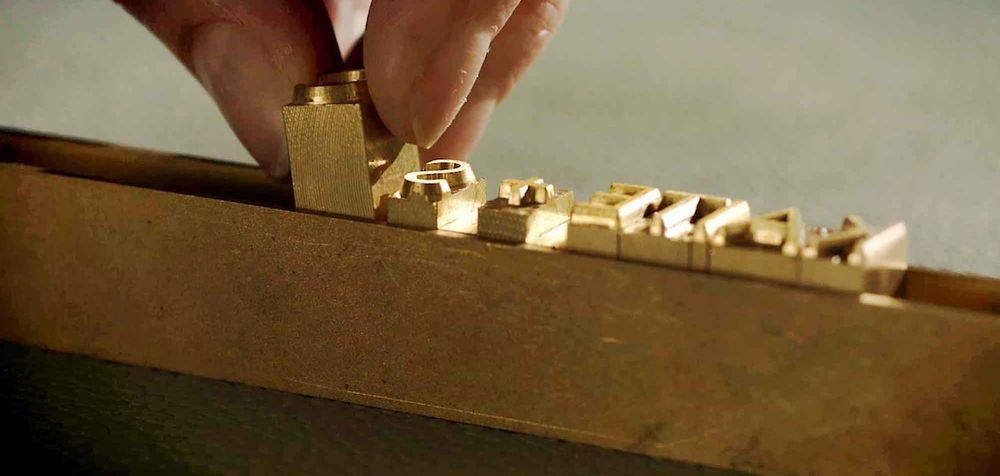 Close-up of brass or gold colored metallic book binding components being assembled.
