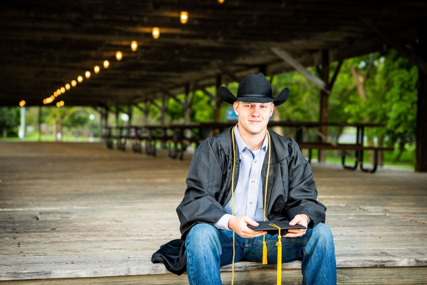 Person seated under wooden pavilion with string lights overhead.