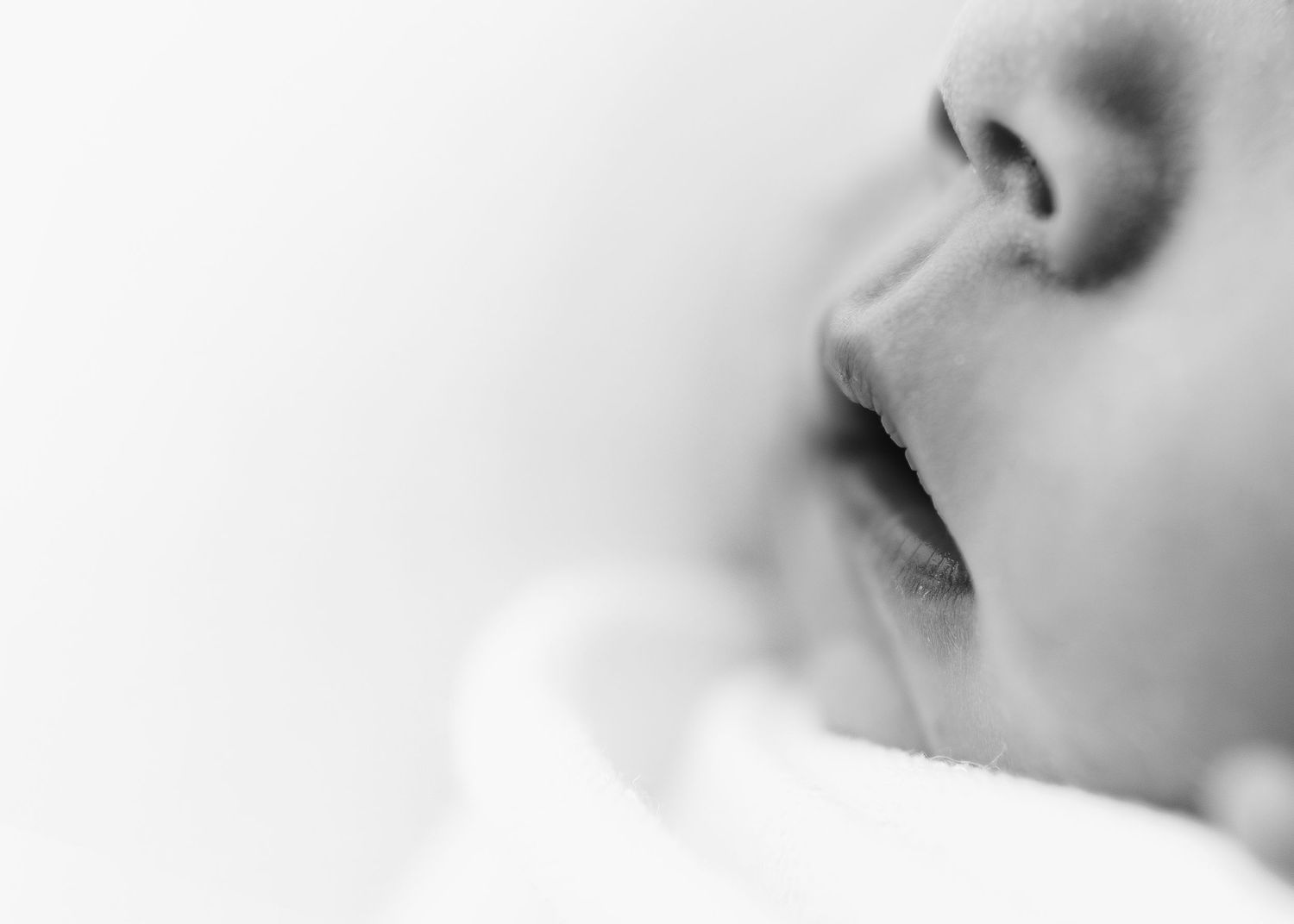 Extreme close up profile of baby's nose and mouth in dreamy black and white photography.