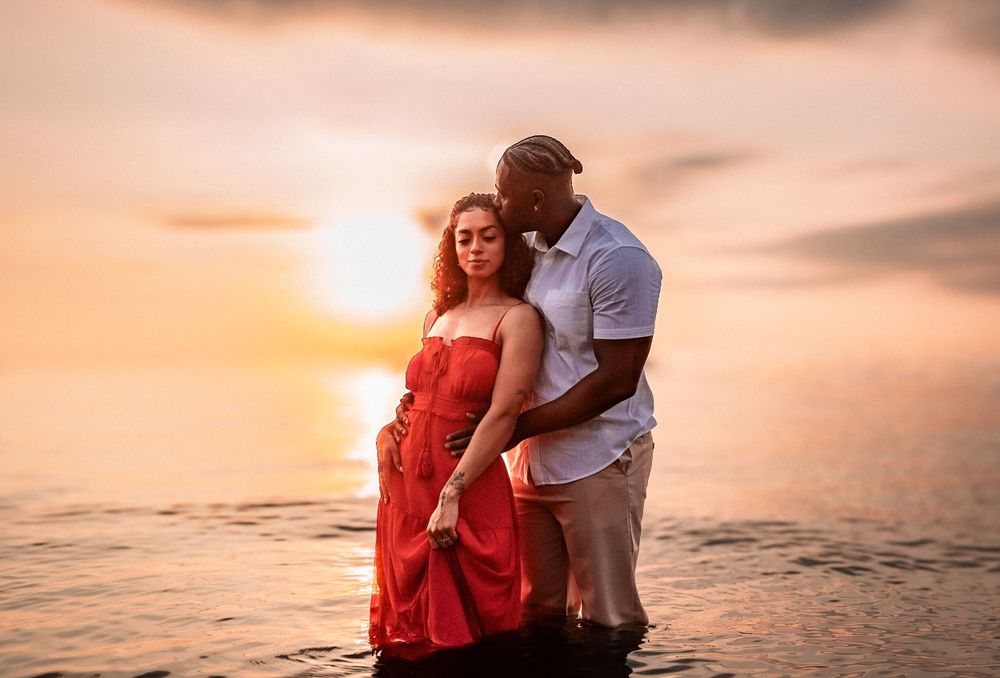 Romantic sunset beach portrait with couple in white and red attire.