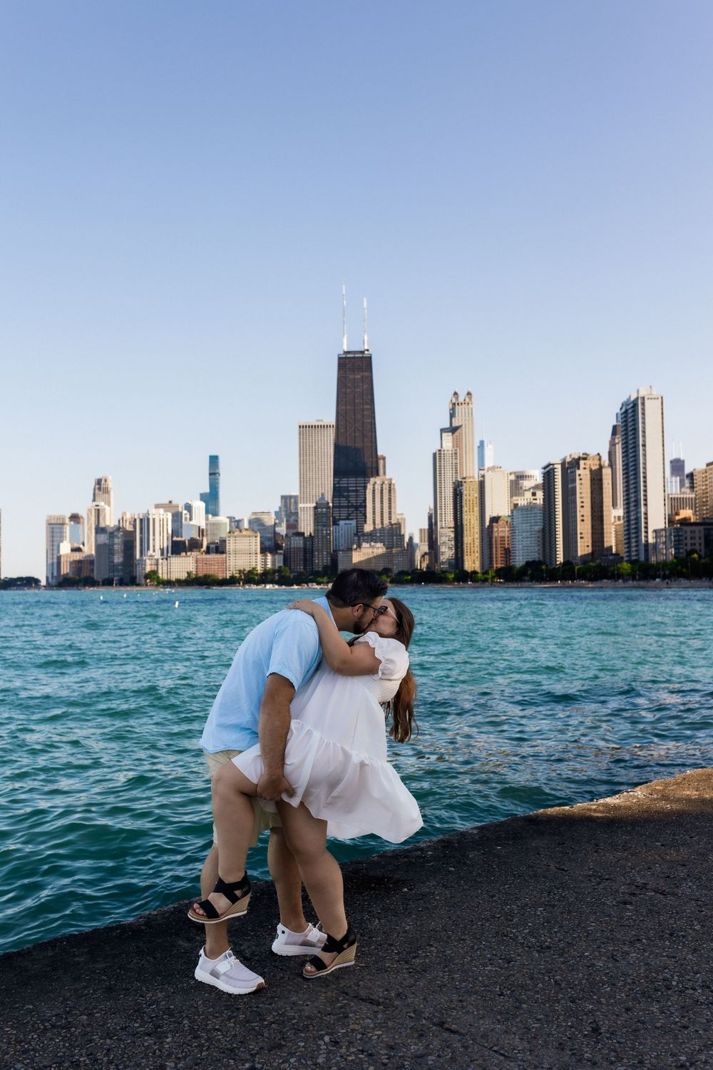 Romantic couple kissing by Lake Michigan with Chicago skyline in background.
