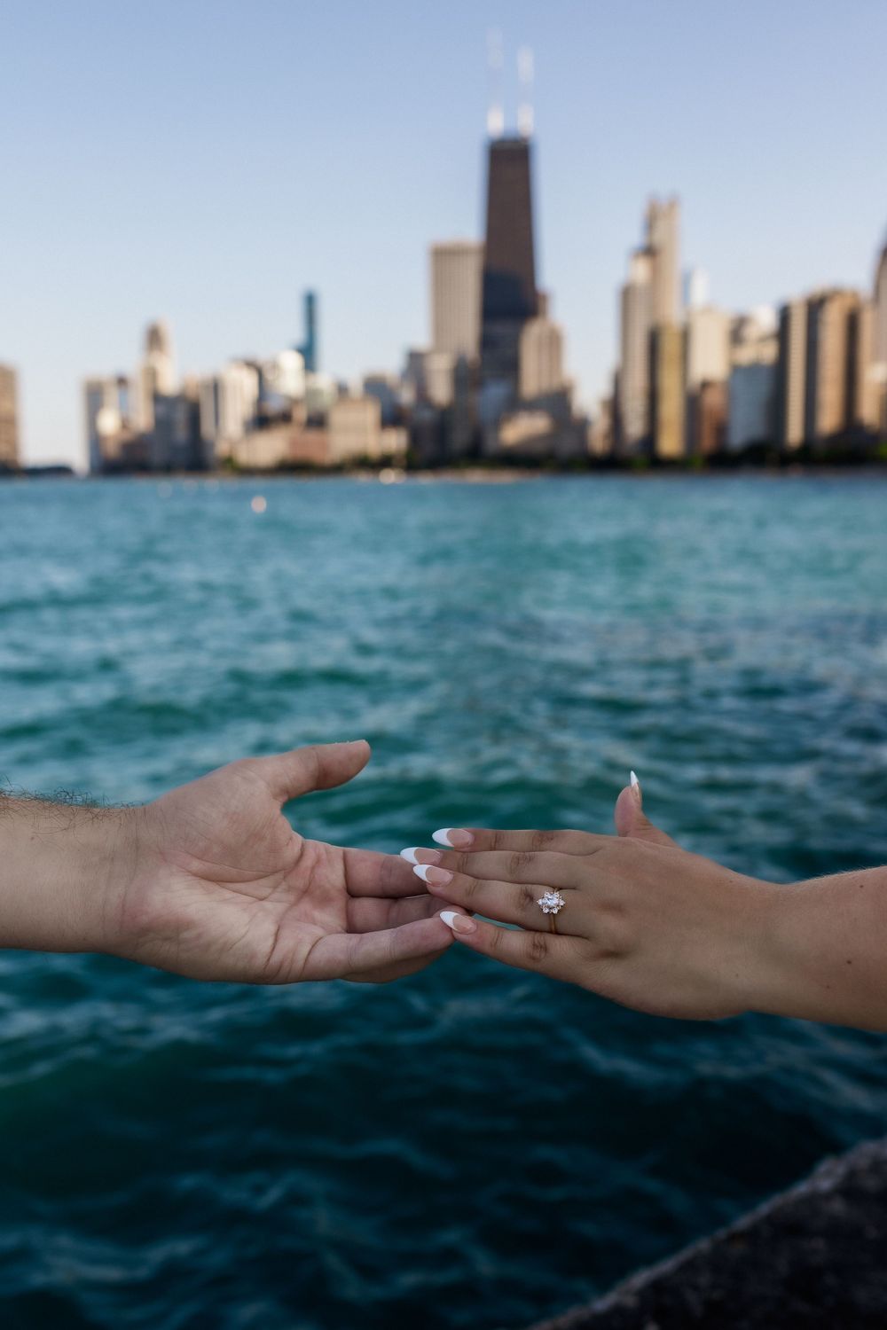 Two hands reaching towards each other with Chicago skyline and Lake Michigan in background.