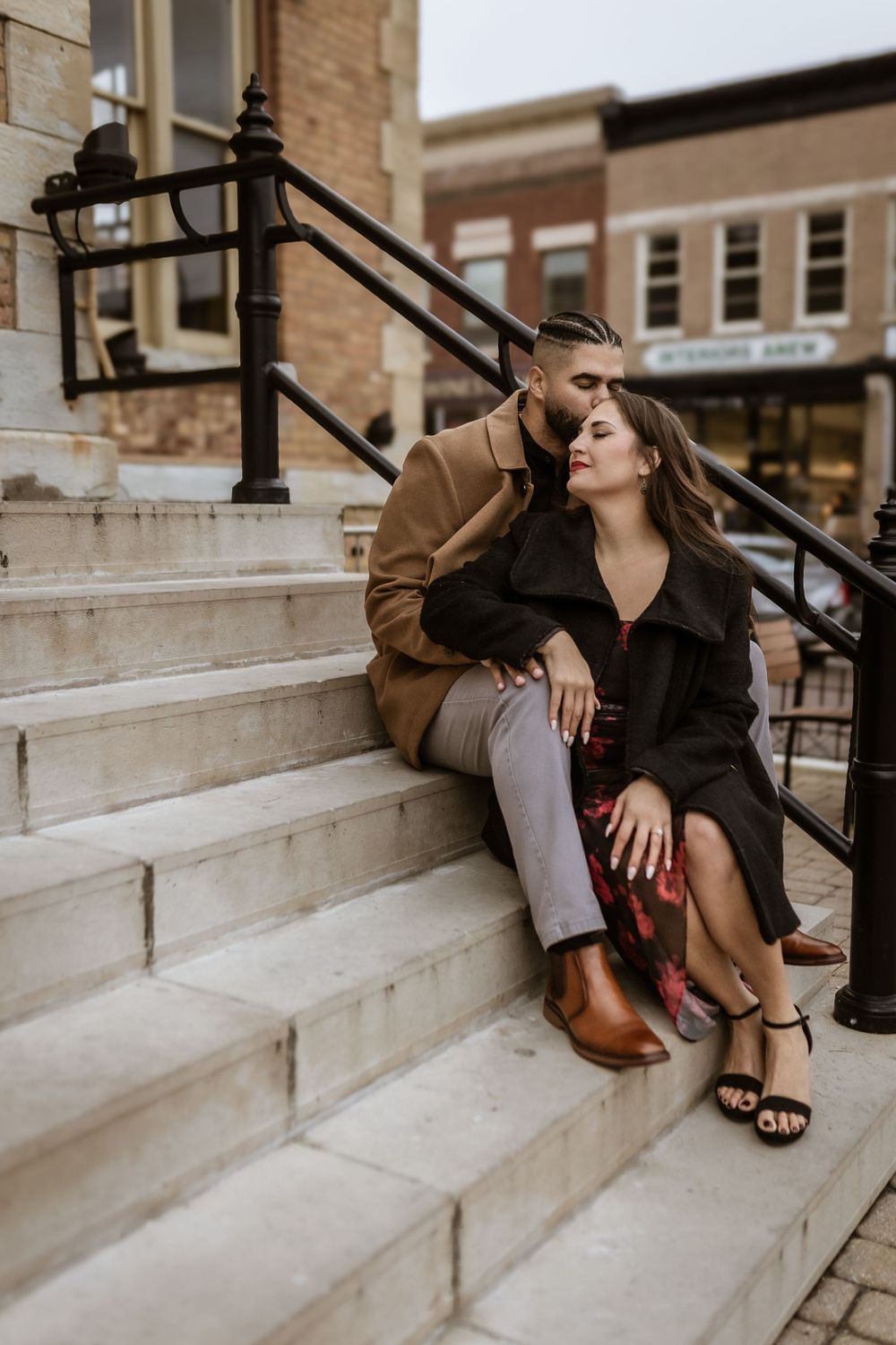 Stylish couple sharing intimate moment on urban stone steps with vintage architecture.