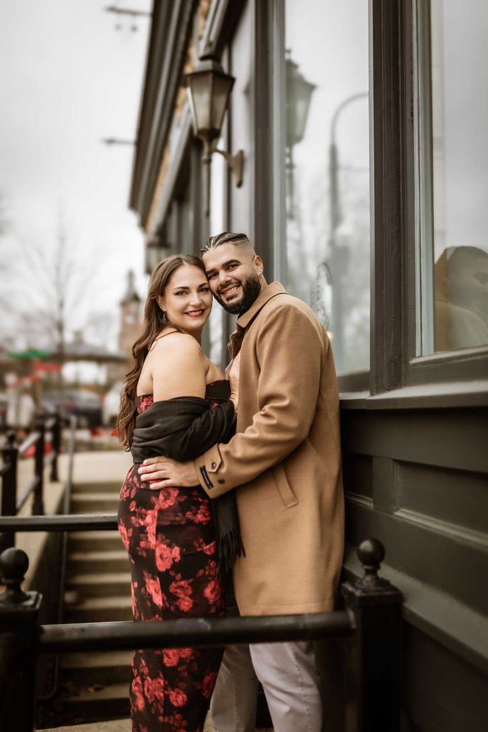 Couple in elegant attire embracing on historic building steps during winter.