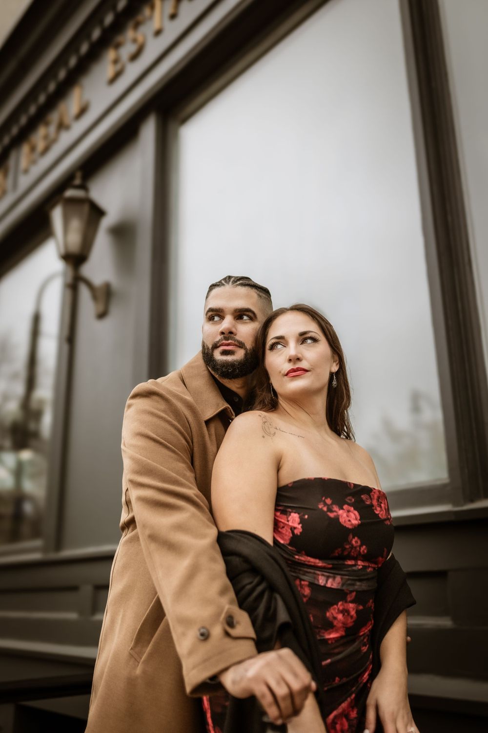 Dramatic upward angle of couple in formal wear against historic building facade.