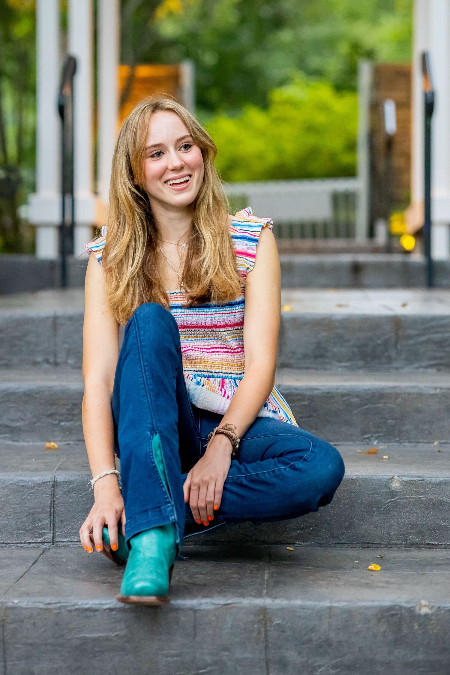 Casual portrait on concrete steps wearing striped top and turquoise boots.