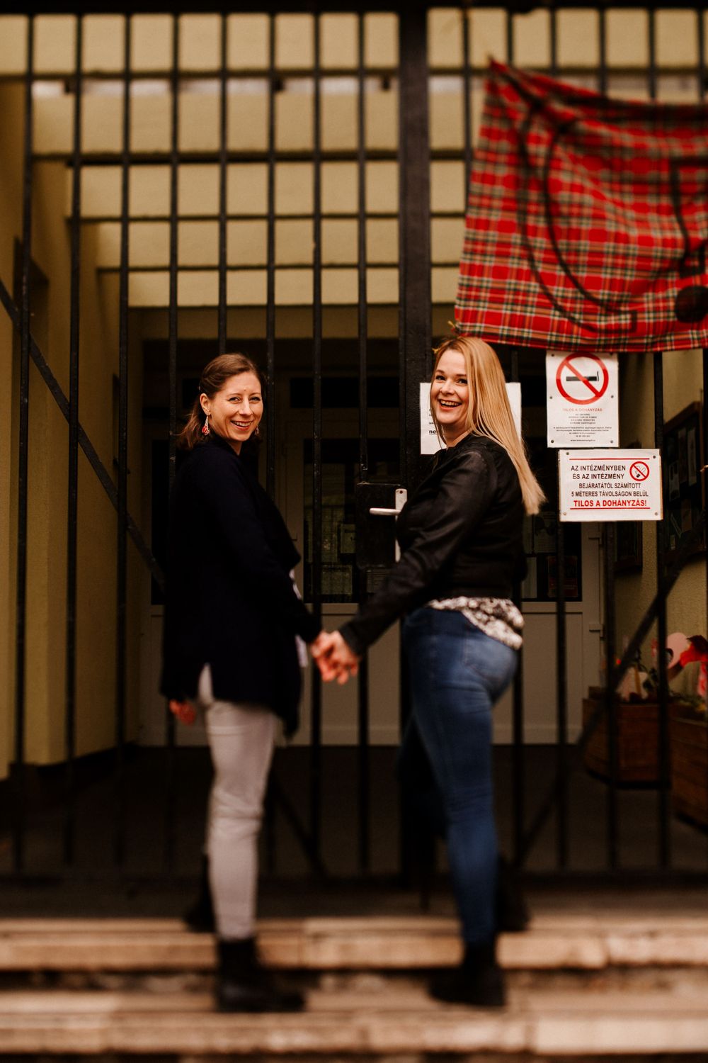 Two people holding hands on steps with a plaid cloth and no smoking sign visible.