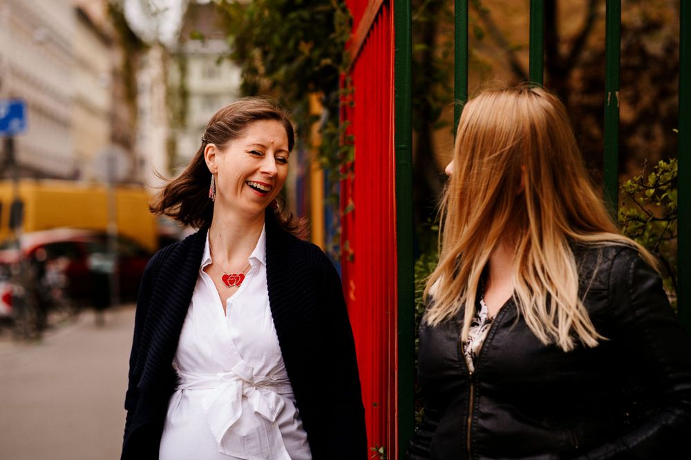 Two people sharing a joyful moment near a bright red pole outdoors.