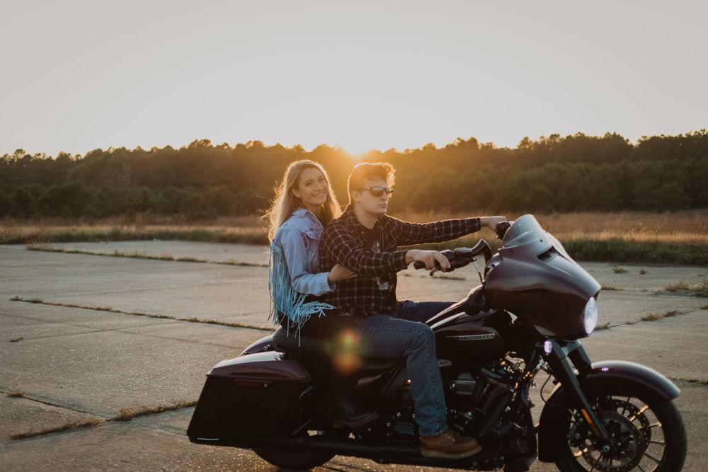 A motorcycle parked on concrete during golden hour with riders enjoying the sunset.