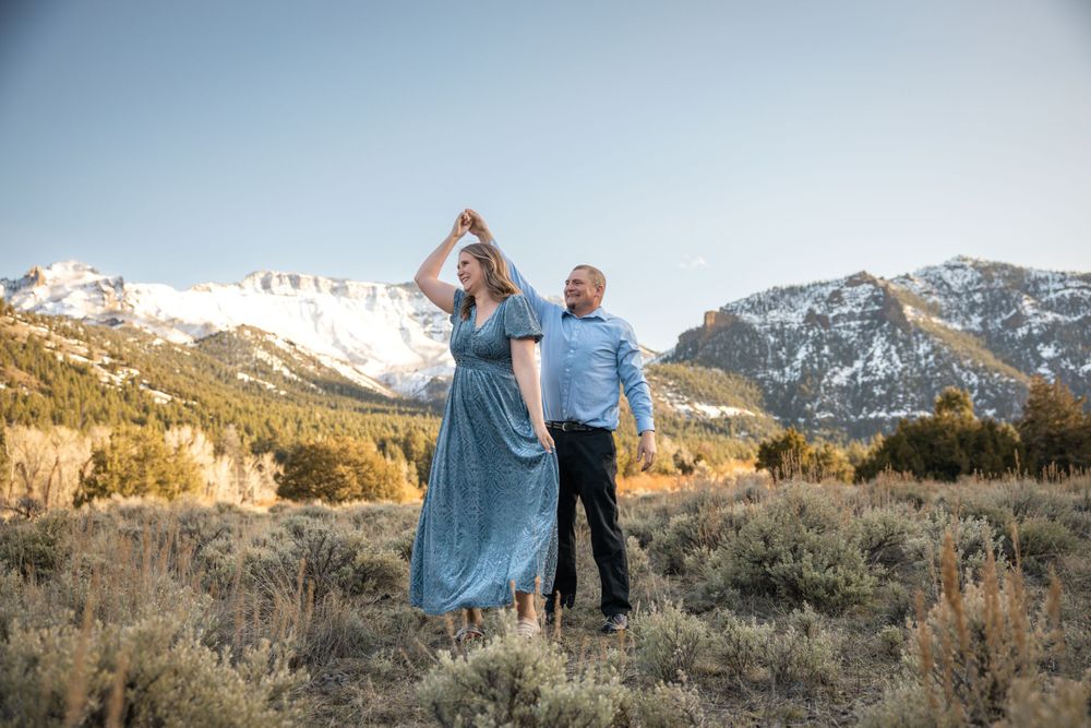 Couple sharing intimate moment against snow-capped mountain landscape.