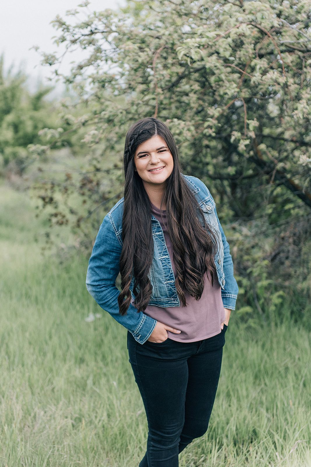 A casual outdoor portrait features someone in a denim jacket against blooming white spring flowers.
