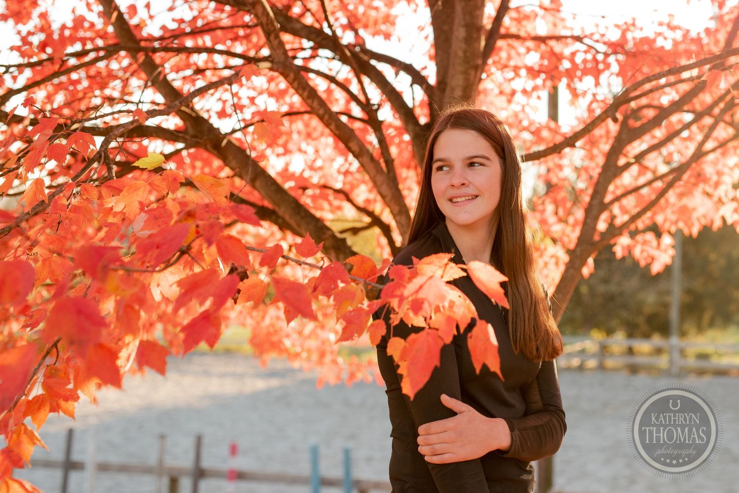 Portrait against vibrant red autumn maple leaves during sunset.