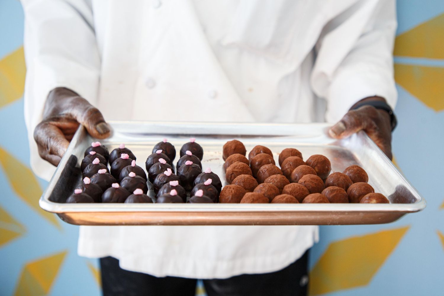 Everett small business photographer: a baker holds a tray of his products at Touba Bakery in Everett
