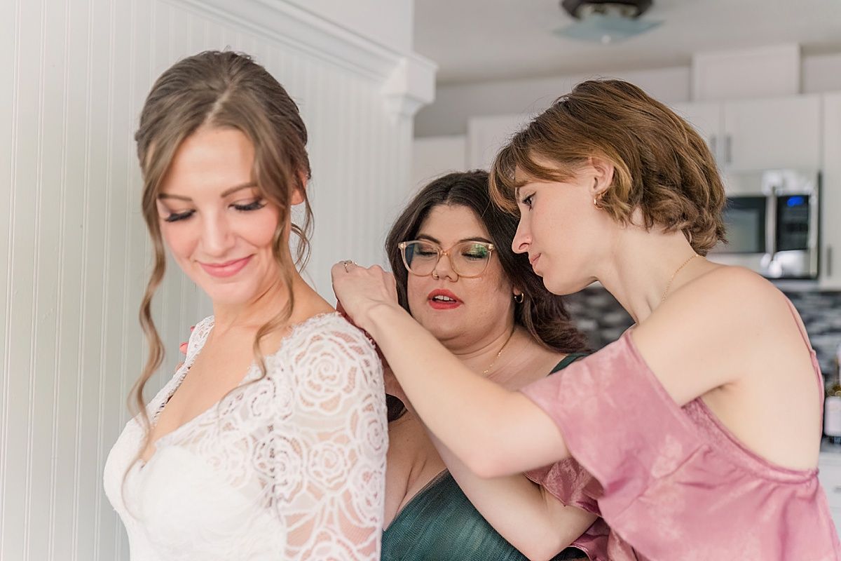 Bridesmaids helping bride with wedding dress