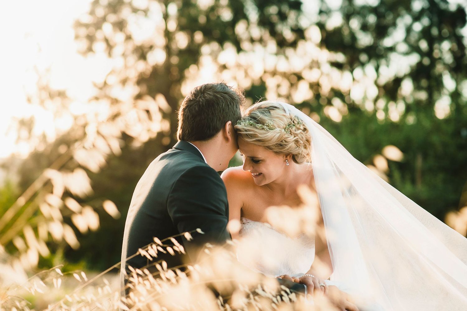 bride and groom in tall grass at sunset