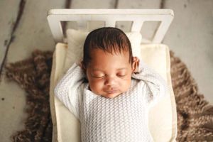 baby with arms behind head on bed