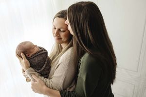 mothers kissing baby in front of window
