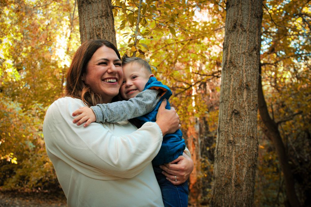 Candid moment of joyful embrace captured during fall outdoor photo session.