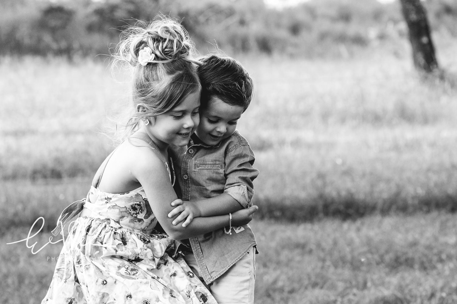 A tender moment captured in black and white on a sunny field.