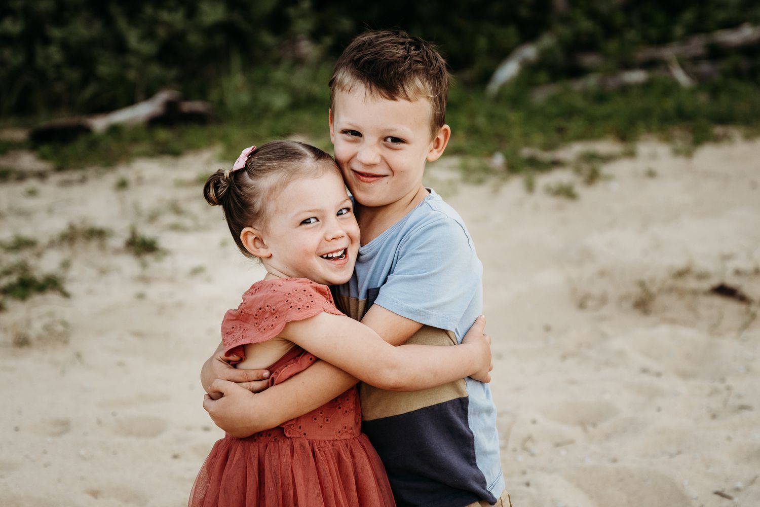 Two young children share a sweet embrace while playing outside on a sunny day.