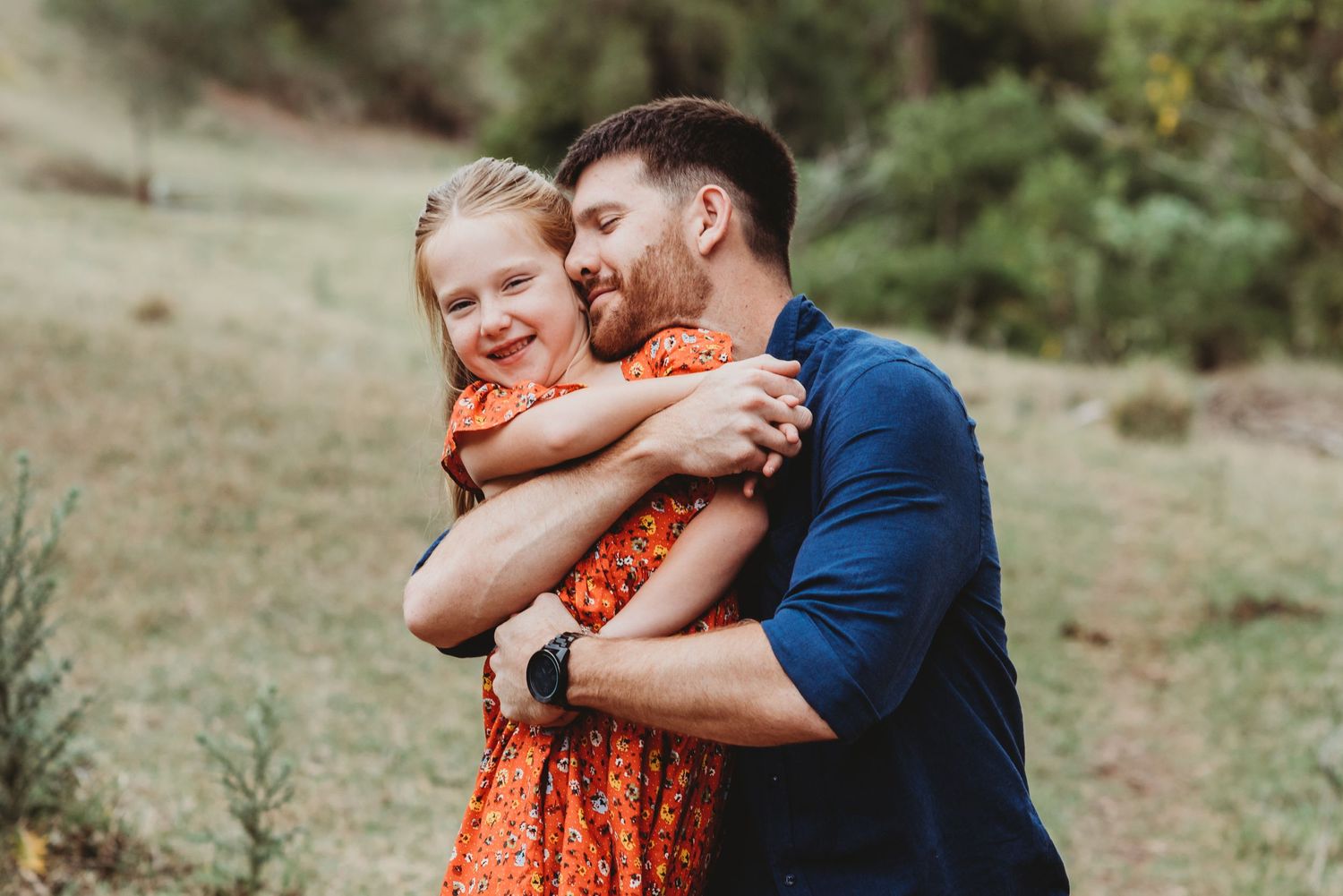 Candid embrace captured during outdoor photo session in natural setting.