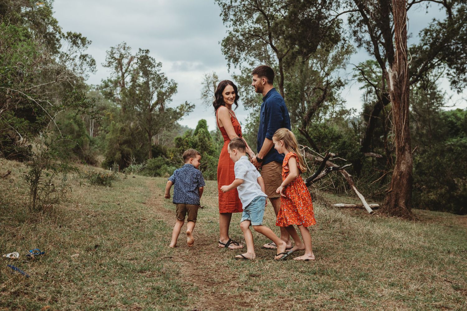 Family dancing together on a grassy hillside with eucalyptus trees in the background.