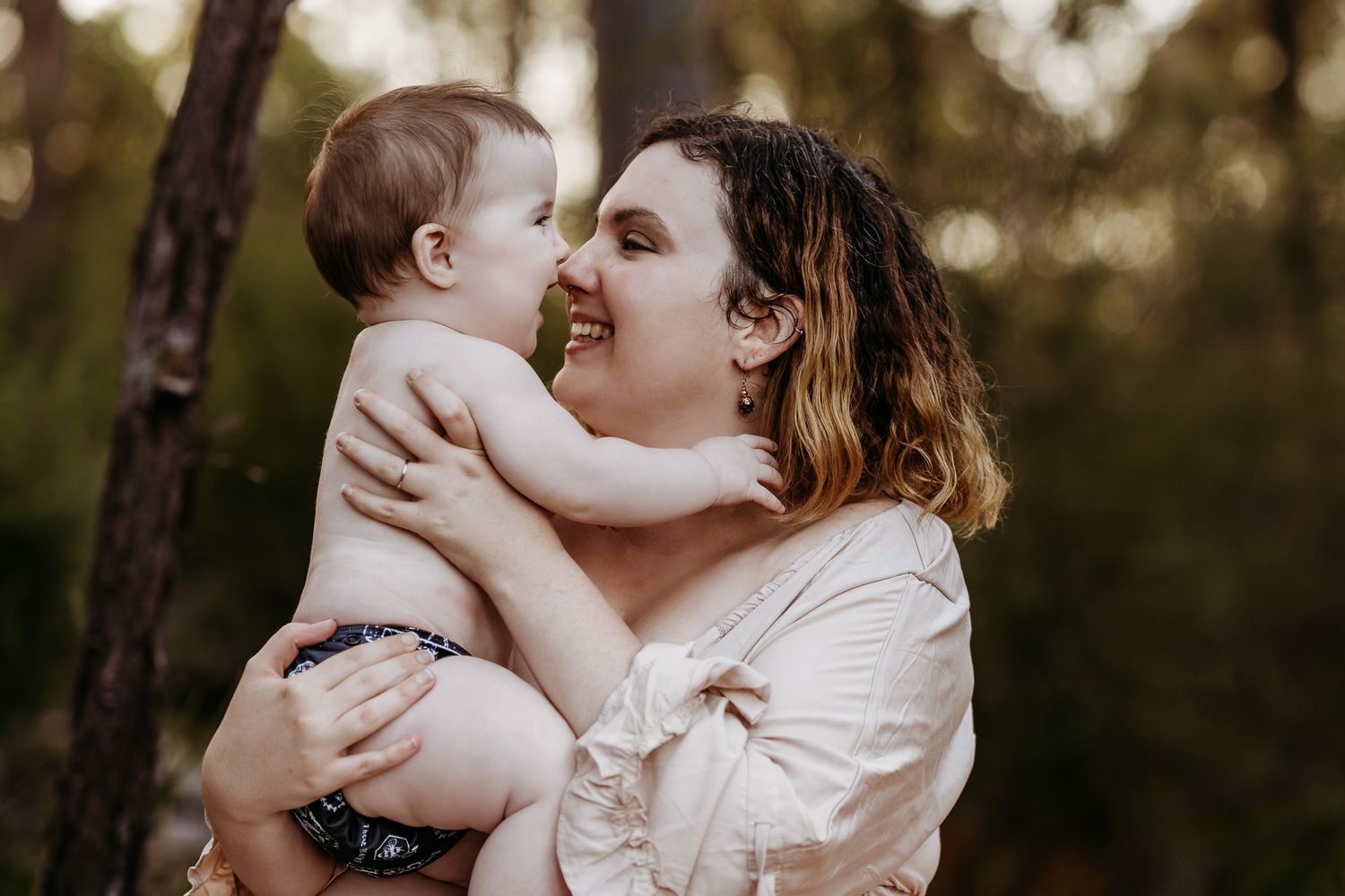 An intimate moment of joy and laughter shared between parent and baby outdoors.