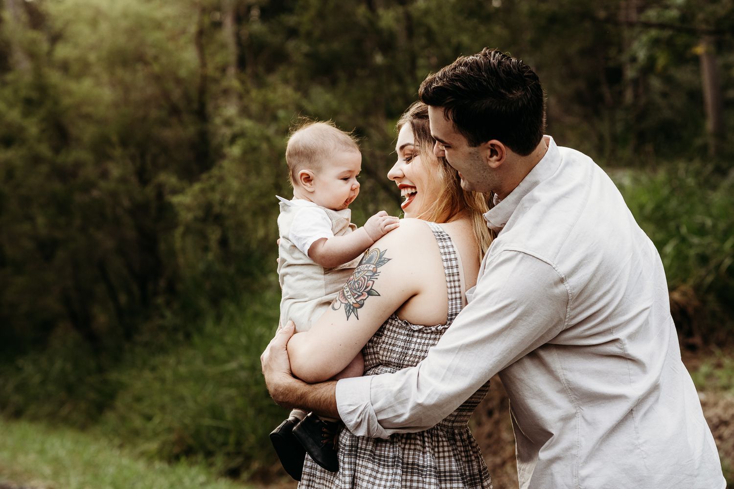 A joyful family moment outdoors with three people embracing and laughing together.