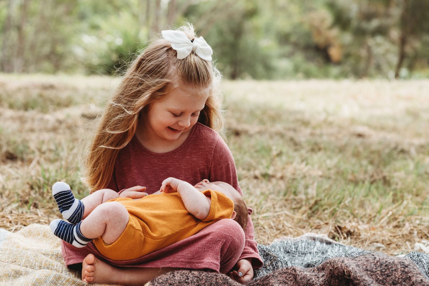 A sweet moment on a blanket outdoors showing gentle interaction with soft toys and autumn colors.