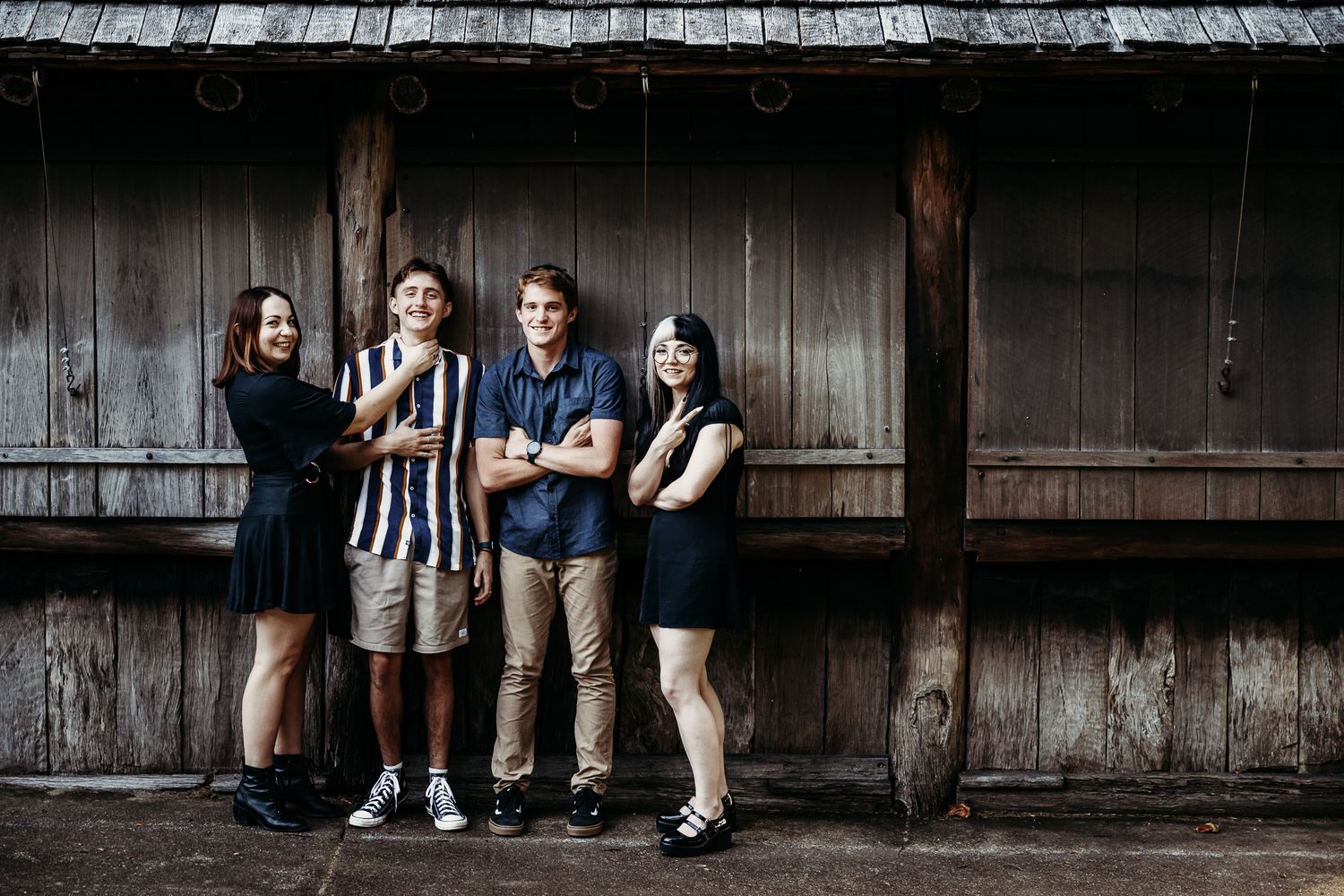 Group portrait of people standing against rustic wooden wall background.
