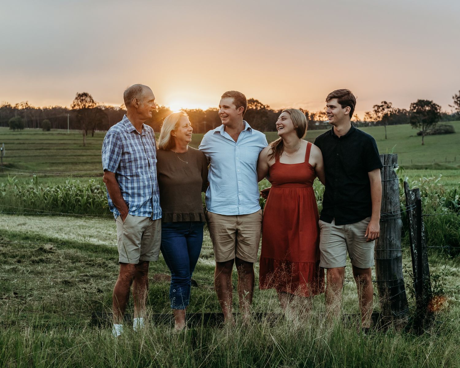Group enjoying sunset together in a pastoral field with rolling hills in the background.