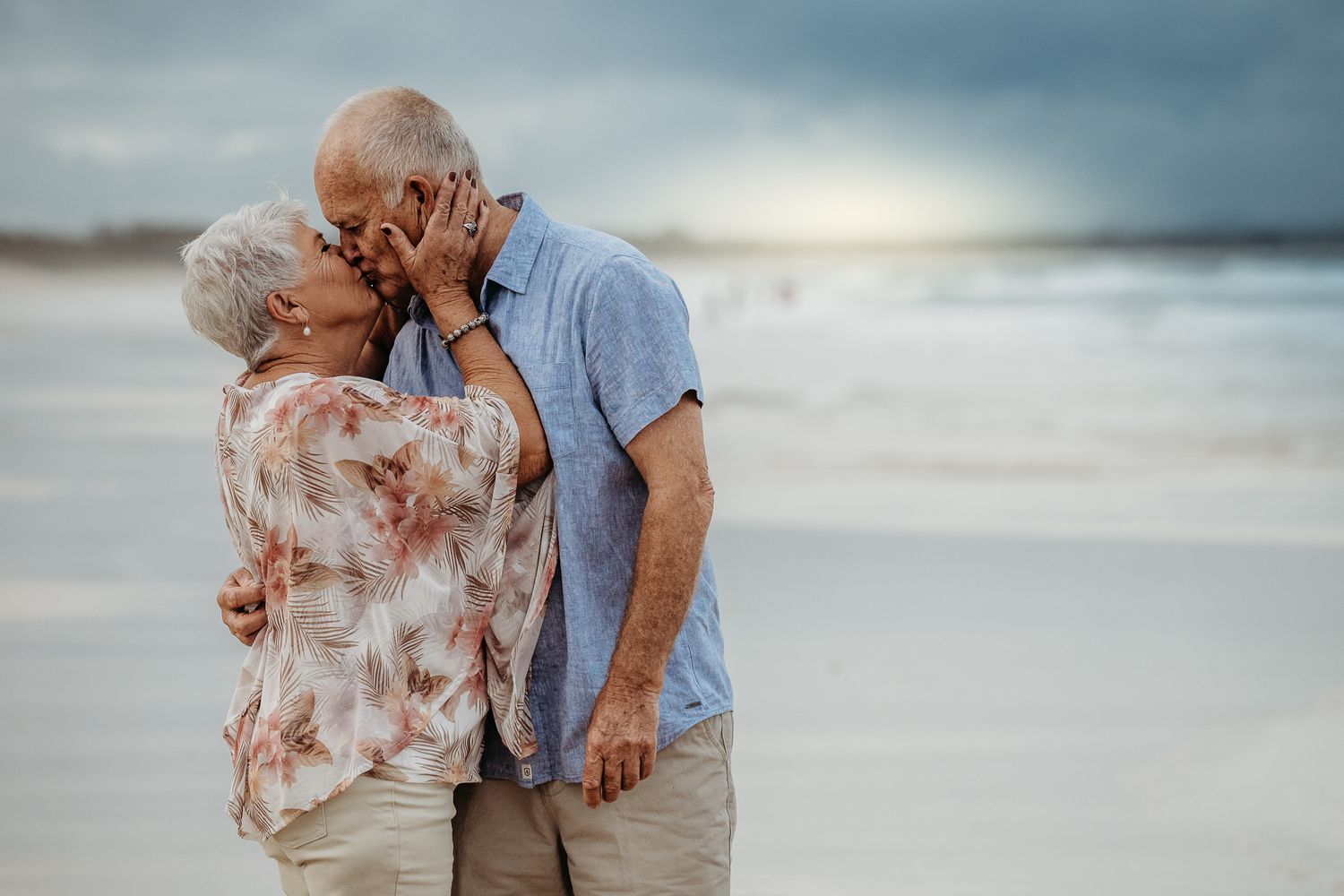 Romantic moment between a couple on a serene beach during sunset.